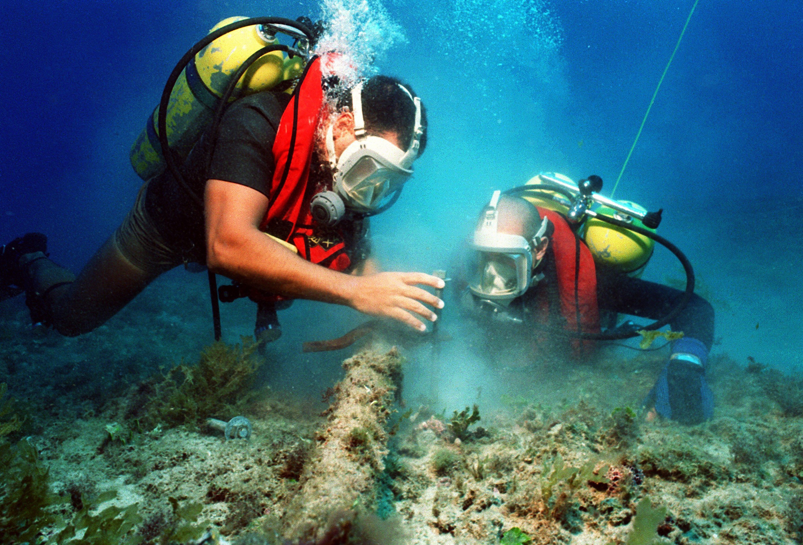 Scuba Divers maintaining a pipe underwater